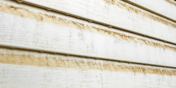 Dirty vinyl siding with stains of dust and water.