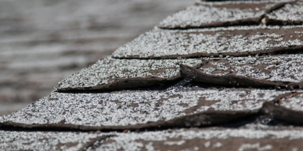 Old worn out asphalt shingles on the roof of a residential home.