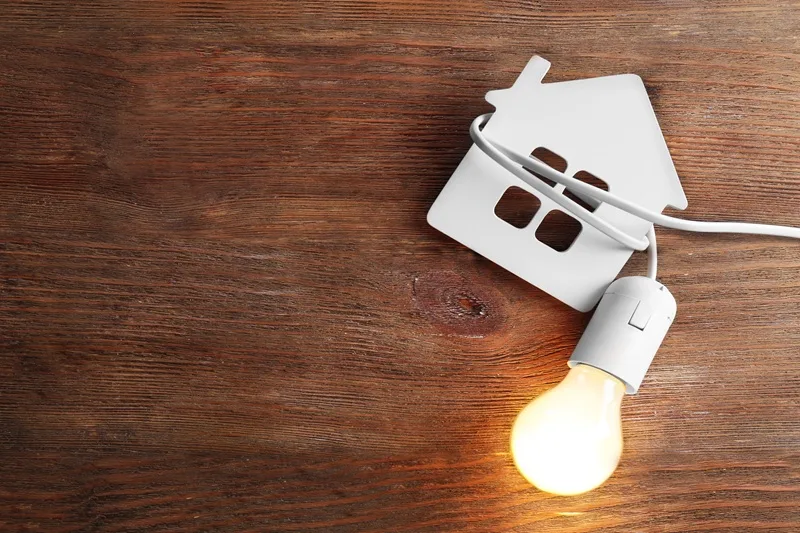 Bulb and shape of home on wooden background