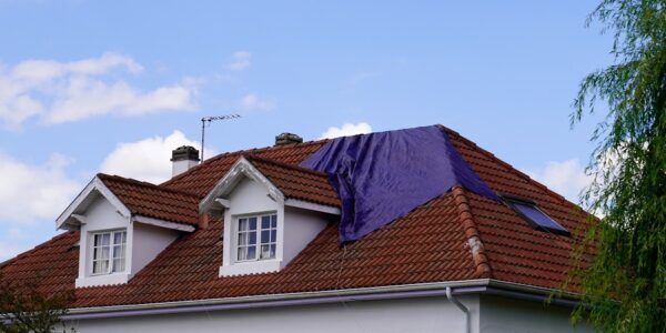 roof experiencing a leak covered with a tarp waiting for the roofing company to fix after spring summer thunderstorm