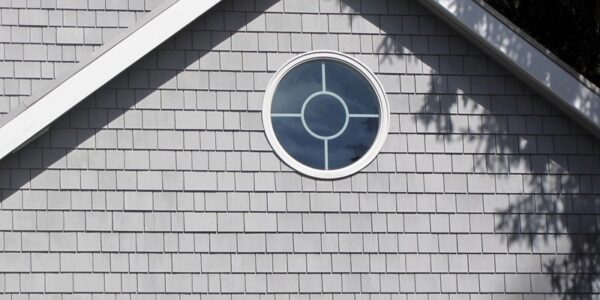 Cedar Shake siding in the color gray with a round window