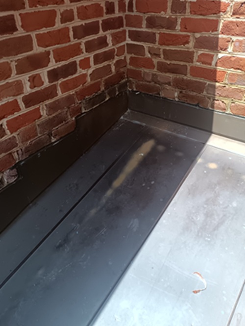 Counter flashing on a copper roof grinded into an old brick wall